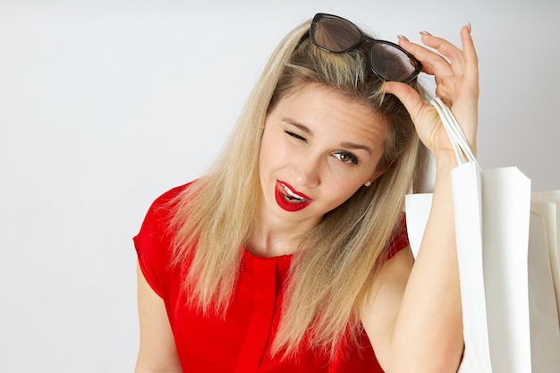 Closeup of beautiful woman taking off her sunglasses and winking in red dress