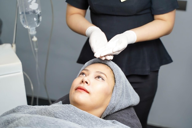 Closeup beauty nurse show of face scrub cream on hands before making facial massage on customer face