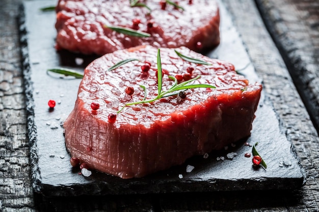 Closeup of beef with rosemary and pepper on black rock