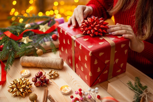 Closeup of big Christmas present in hands of a girl making last touches to it