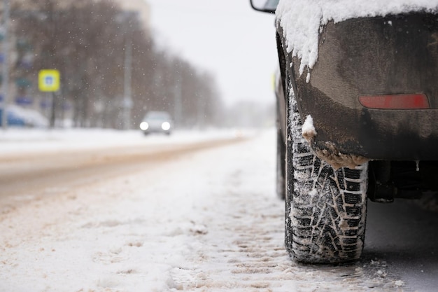 Closeup of a black car with a studded wheel on the background of the road and passing cars