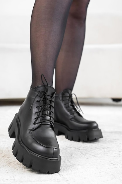 Closeup black elegant shoes on women's legs. Leather winter boots, stylish lady footwear concept photo