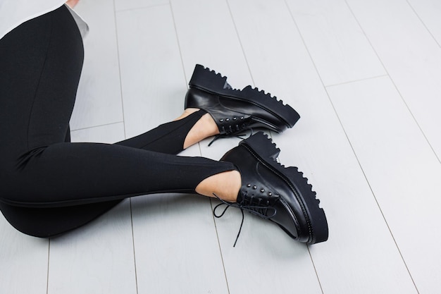 Closeup of black leather laceup shoes on female legs in black leggings Women's stylish autumn shoes