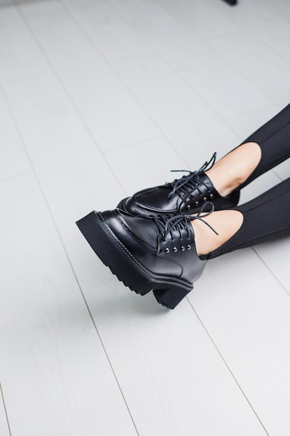 Closeup of black leather laceup shoes on female legs in black leggings Women's stylish autumn shoes