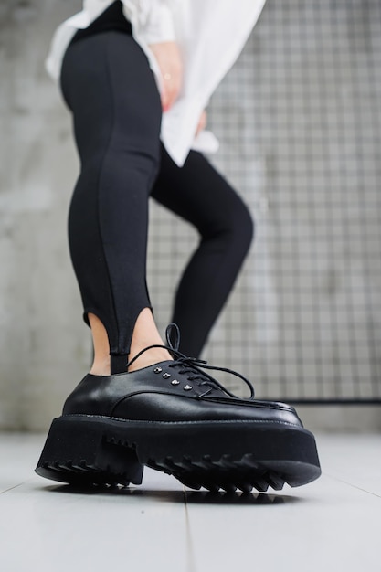 Closeup of black leather laceup shoes on female legs in black leggings Women's stylish autumn shoes