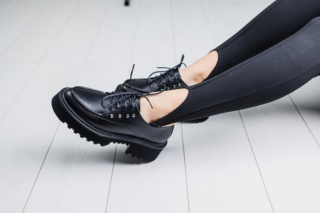 Closeup of black leather laceup shoes on female legs in black leggings Women's stylish autumn shoes