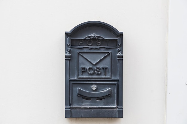 Closeup of a black metal mailbox on a white stone building