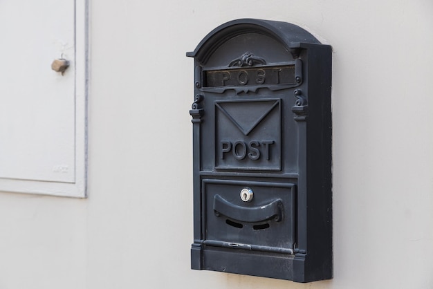 Closeup of a black metal mailbox on a white stone building