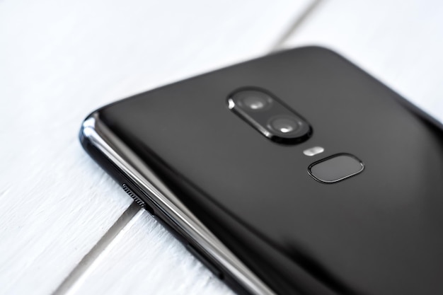 Closeup black modern smartphone on the white wooden table