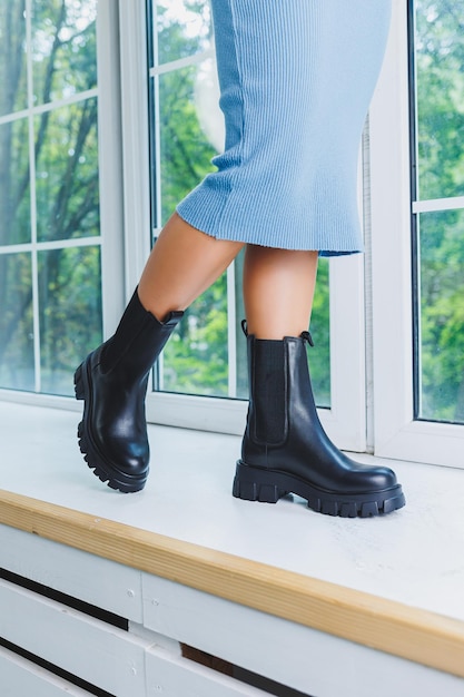 Closeup of black women's boots Black boots made of genuine leather Closeup photo of a woman's legs in warm boots