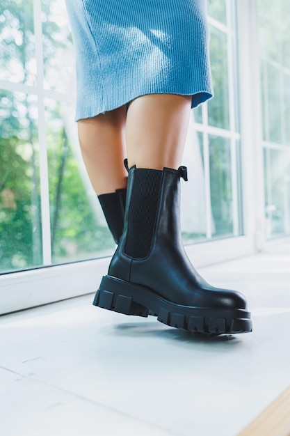 Closeup of black women's boots Black boots made of genuine leather Closeup photo of a woman's legs in warm boots