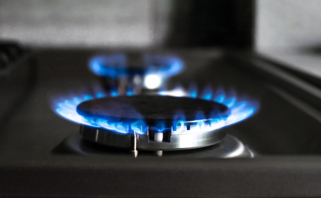 Closeup of a blue fire from a kitchen stove two gas burners with a burning flame economy concept