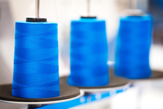 Closeup bobbins with blue colored thread for industrial textile machines