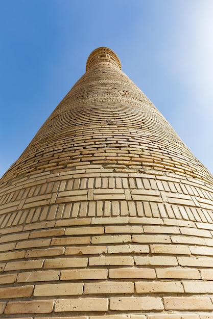 Closeup bottom to top view of ancient brick minaret against clear blue sky Bukhara Uzbekistan