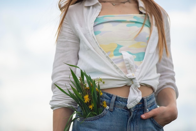 Closeup of a bouquet of wildflowers from the pocket of a teenage girl's denim pants