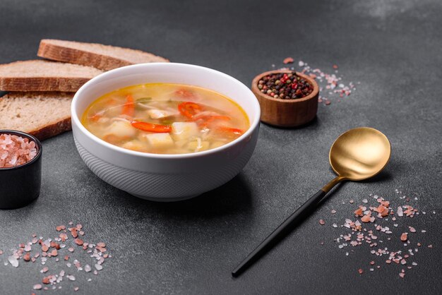 Closeup of a bowl of chicken noodle and vegetable soup on a concrete table