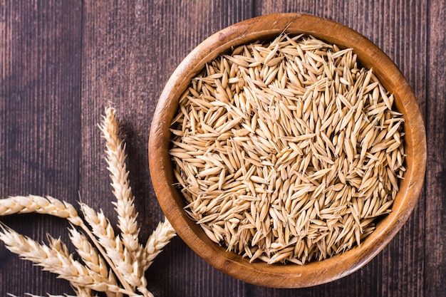 Closeup of a bowl with oat seeds and ears of oats on the table Organic harvest