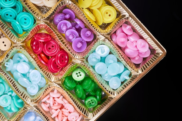 Closeup of a box with a set of multicolored buttons in plastic cells