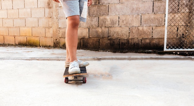 Closeup of a boy practicing standing on a skateboard with his dog