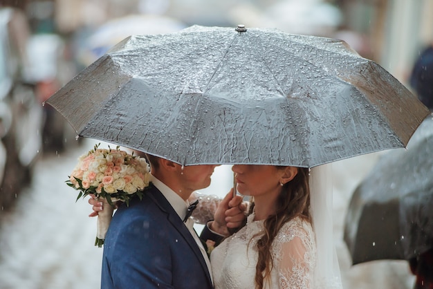 Closeup of bride and groom walking under umbrella on their wedding day