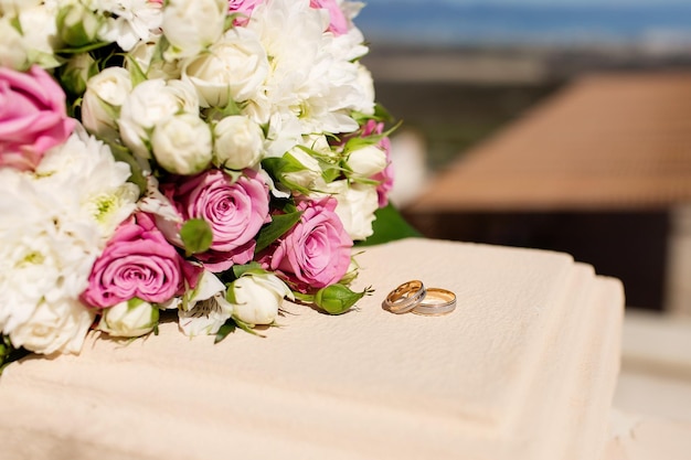 Closeup of the bride's bouquet of pink roses and wedding rings Wedding