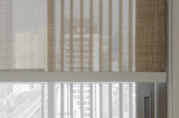 Closeup brown color roller blinds curtains sunlight through the windows in the city