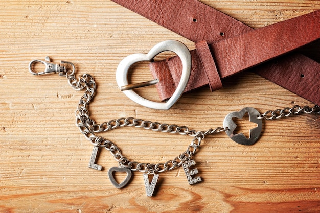 Closeup brown leather woman belt with metal heart shaped belt buckle and LOVE wallet chain