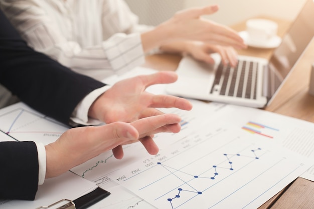 Closeup of business colleagues hands working with documents, using laptop and having troubles. Financial background, count and pay an account, copy space