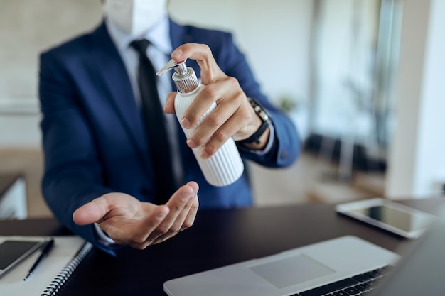 Closeup of businessman disinfecting hands in the office