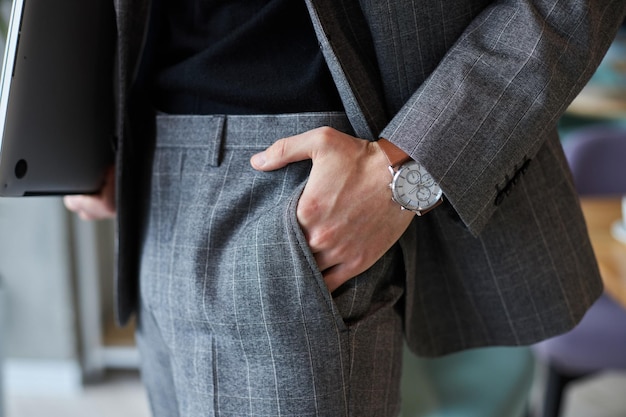 Closeup of a businessman in formal suit holding his hand wearing stylish wrist watch in the pocket