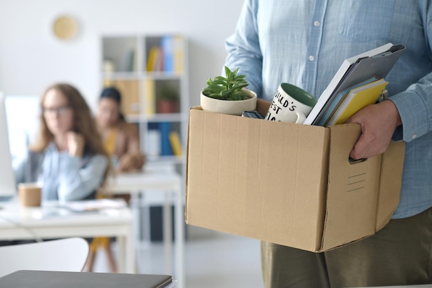 Closeup of businessman standing with box with office stuff after his layoff