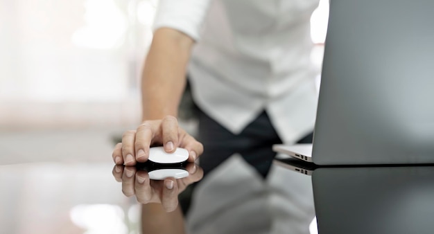 Closeup businessman using computer mouse with laptop at office desk