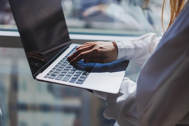 Closeup of businessman using laptop typing on keyboard sitting at wooden table writing email accountant writing financial report busy student studying online looking for information