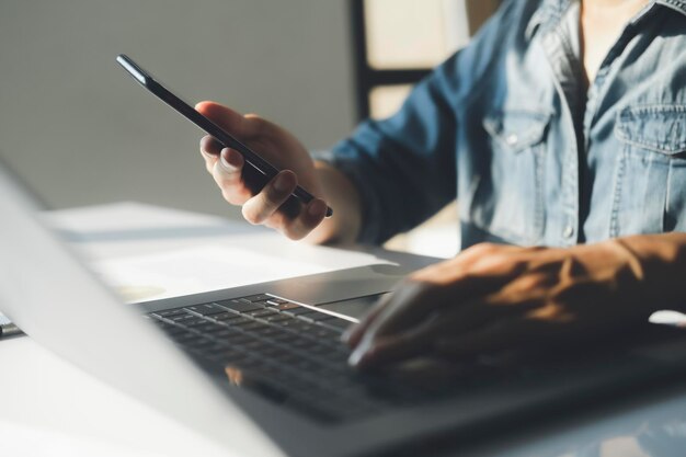 Closeup of businessman using on smartphone and laptop He is looking at his finances statistics and business