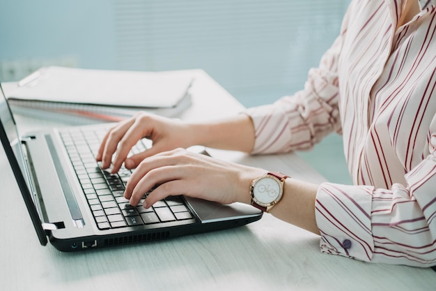 Closeup of businesswoman hand making notes in calendar on laptop female hand typing