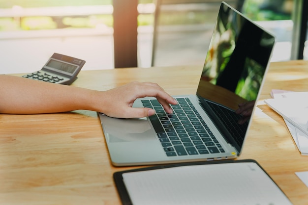 Closeup of businesswoman hands on laptop at office desk woman using laptop for searching web or browsing information home office concept