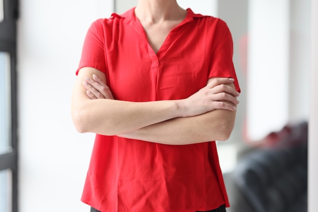 Closeup of businesswoman in red blouse crossed hands on chest defensiveness gesture