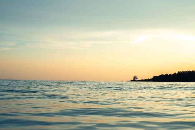 Closeup calm ocean waves breaking on summer coast at orange sunrise morning Yellow sunlight reflect