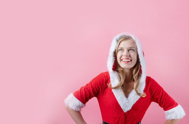 Closeup of caucasian happy woman wearing santa clothes against pink background copy space