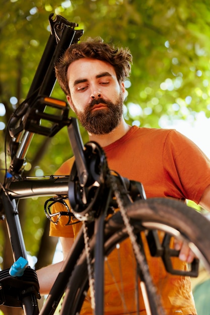 Closeup of caucasian male cyclist securing his bike wheel ensuring a safe and enjoyable recreational cycling experience Outdoor activity of young athletic man maintaining bicycle tire and chain ring