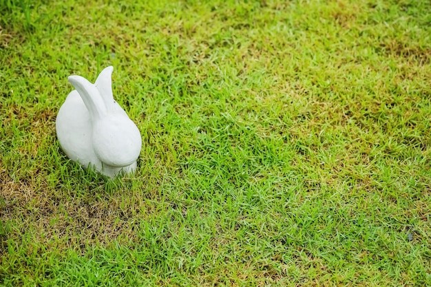 Closeup cement rabbit statue for decoration on grass floor in the garden background