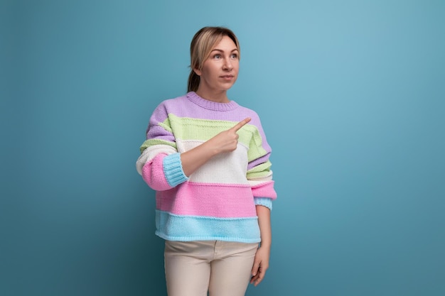 Closeup of charming blond young woman in casual outfit looking away on blue background with copy