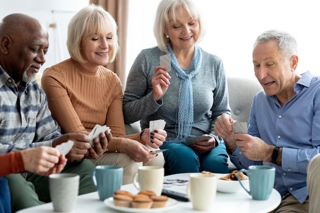 Closeup of cheerful elderly people chilling together playing cards