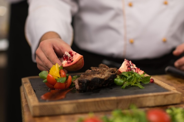 closeup of Chef hands in hotel or restaurant kitchen preparing beef steak with vegetable decoration