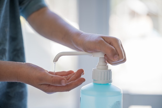 Closeup of a child using hand sanitizer disinfectant in times of global virus pandemic.