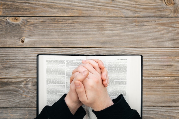 Photo closeup christian read bible hands folded in prayer on a holy bible on wooden background top view