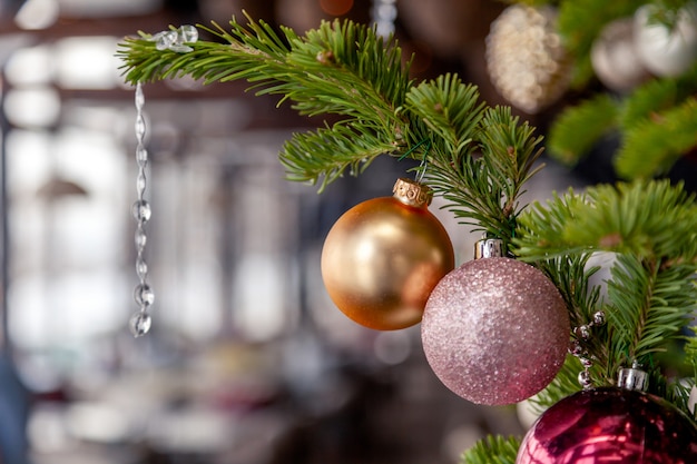 Closeup christmas new year decoration, fir spruce branches with shiny festive toys golden and pink balls.