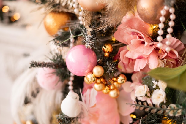 Closeup of a Christmas tree decorated with pink flowers and golden balls