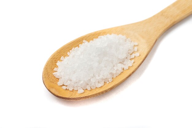 Closeup of coarse salt on a wooden spoon isolated over white background.