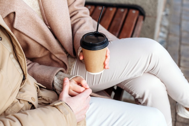 Closeup of coffee cups in hands of young couple having fun together on the street